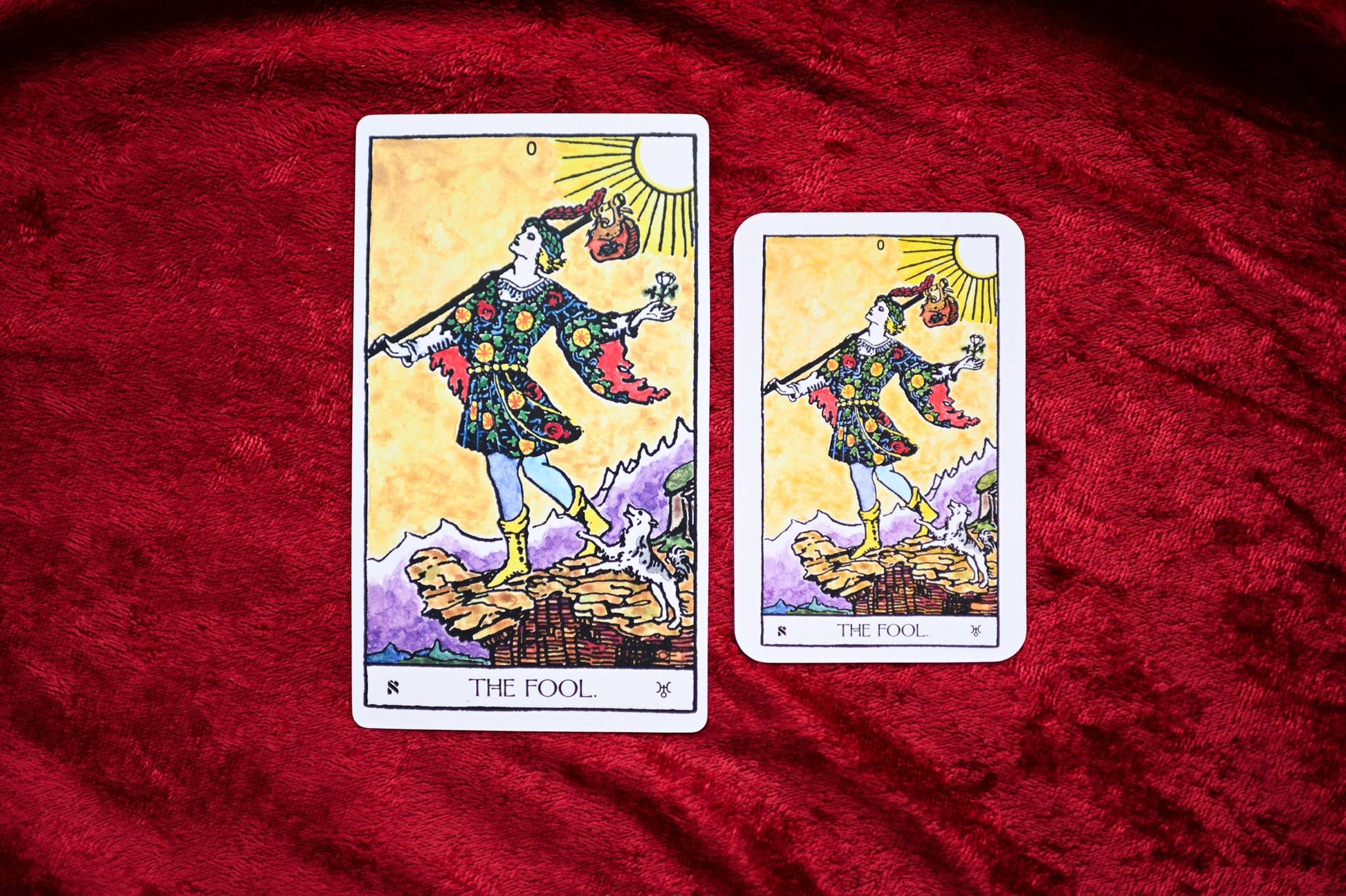 Two tarot cards titled 'The Fool' on a red fabric background