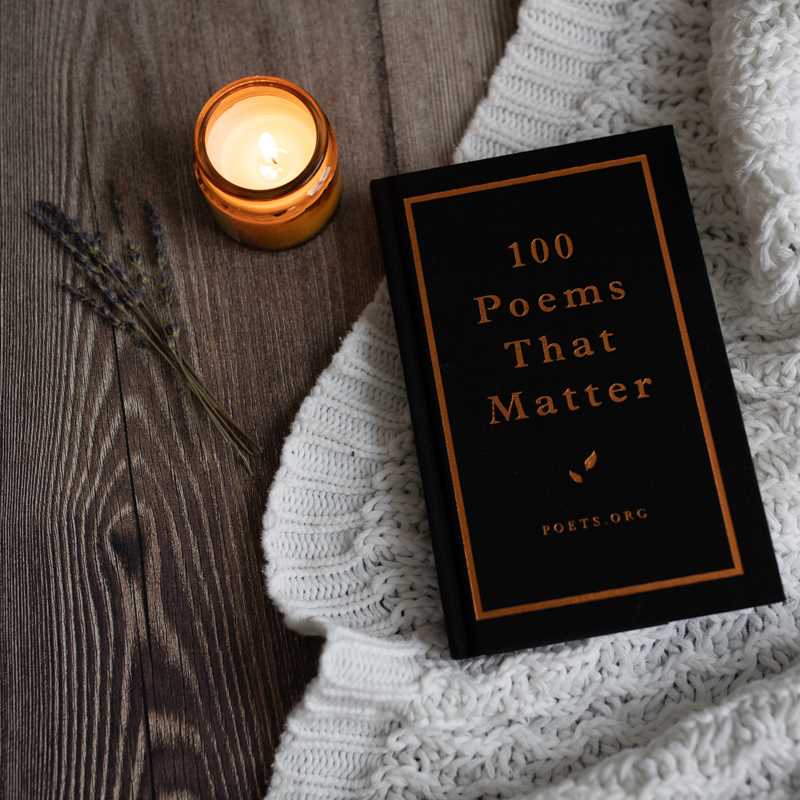 Book titled '100 Poems That Matter' next to a lit candle on a textured surface