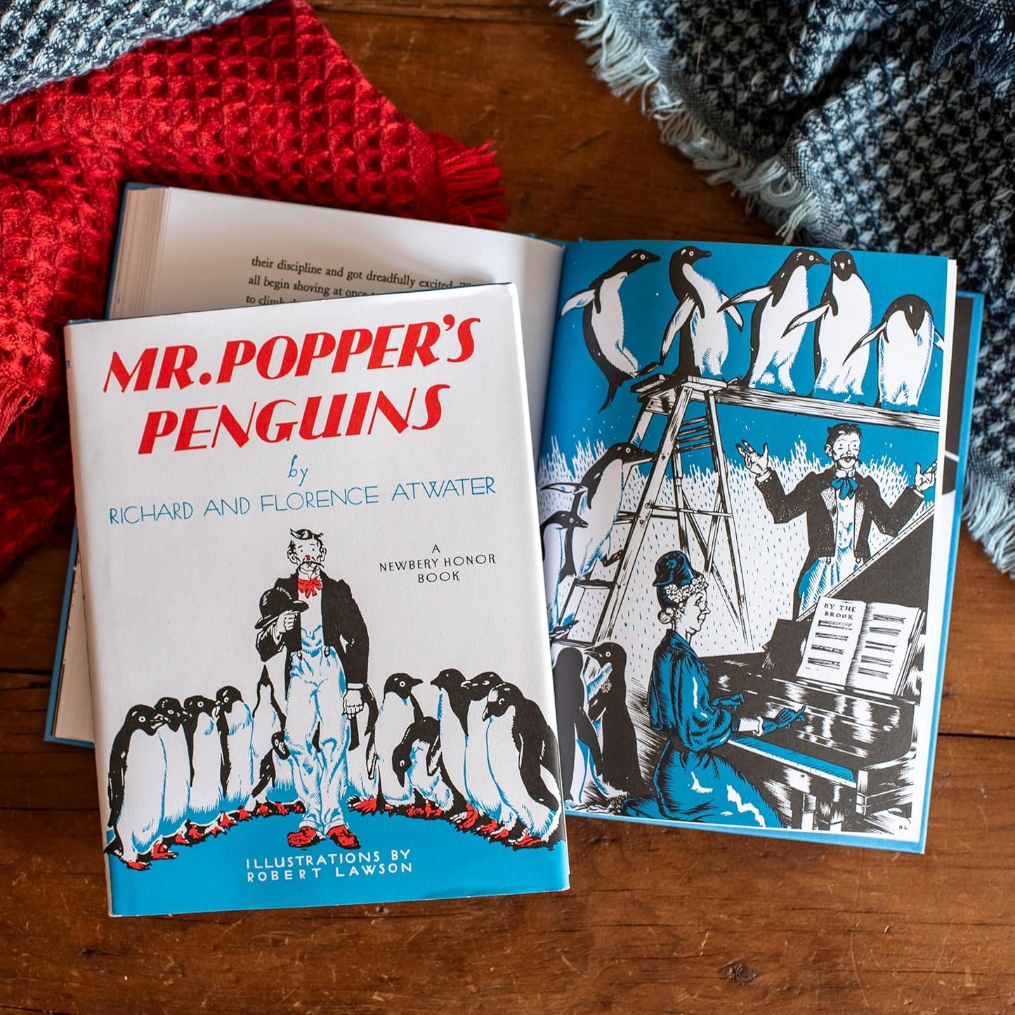 Book titled 'Mr. Popper's Penguins' with illustrations on a wooden surface.