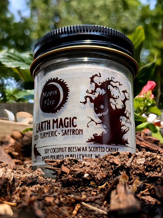 Scented candle jar labeled 'Earth Magic' with nature-themed design on a natural background and Moonfire branding.