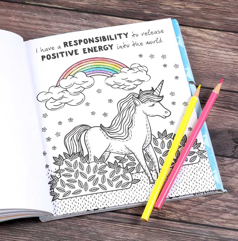 Coloring book with unicorn and rainbow illustration on a wooden surface with two pencils.